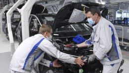 Zamestnanci s ochrannými rúškami pracujú na výrobnej linke nemeckej automobilky Volkswagen.