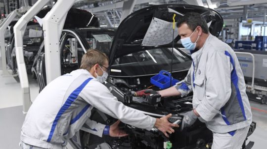 Zamestnanci s ochrannými rúškami pracujú na výrobnej linke nemeckej automobilky Volkswagen.