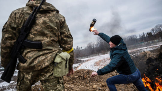 Muž hádže Molotovov koktejl pri bojoch o mesto Cherson na Ukrajine.