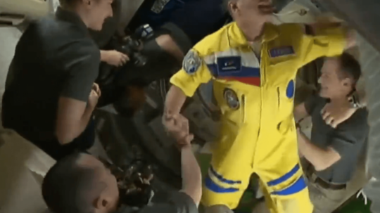 Na snímke ruský kozmonaut v žlto-modrej kombinéze dorazil na Medzinárodnú vesmírnu stanicu.