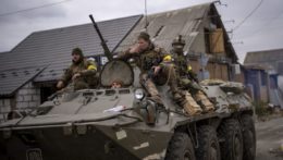 Ukrajinskí vojaci prechádzajú predmestím Kyjeva v obrnenom vozidle.