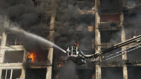 Požiarnici hasia horiacu bytovku v Kyjeve po ruskom bombardovaní.