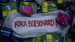 Zväčšený model menštruačnej vložky s nápisom v portugalčine "Bolsonaro preč" sa nachádza medzi darovanými balíčkami menštruačných vložiek počas protestu proti brazílskemu prezidentovi Jairovi Bolsonarovi.