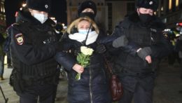 Policajti zatýkajú ženu počas protestu proti ruskému útoku na Ukrajinu.