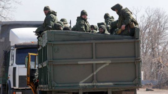 ruskí vojaci sedia na korbe vojenského vozidla