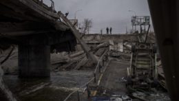 Ukrajinskí vojaci stoja pred zrúteným mostom v meste Irpiň,