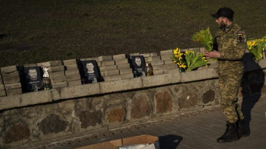 Ukrajinský vojak kladie kvety na pamiatku padlým vo vojne s Ruskom.
