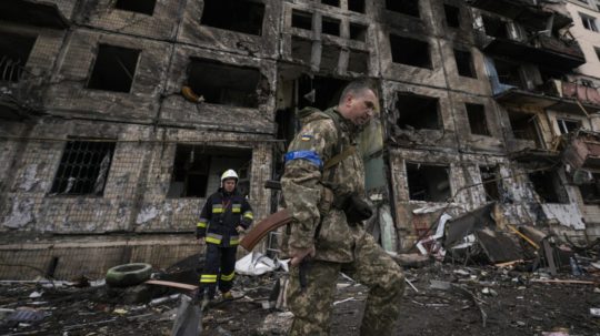 Ukrajinskí vojaci a hasiči prehľadávajú obytný dom v Kyjeve po bombovom útoku.