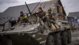 Ukrajinskí vojaci prechádzajú predmestím Kyjeva v obrnenom vozidle.