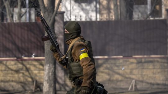 Ukrajinský vojak beží so zbraňou v ruke v Kyjeve.