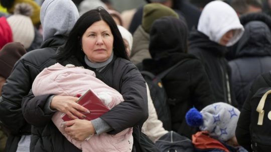 Utečenka utekajúca pred vojenským konfliktom na Ukrajine nesie na rukách dieťa.