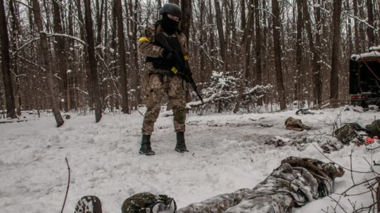 Ukrajinský vojak stojí nad telom ruského vojaka.