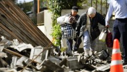 Obyvatelia kráčajú cez trosky zničených domov po zemetrasení v Japonsku.