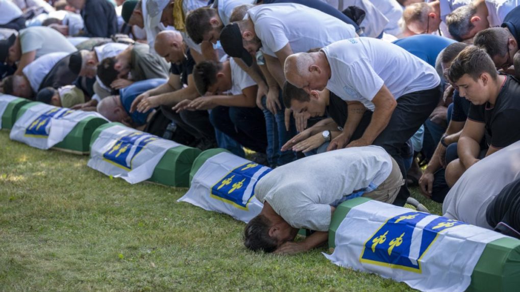 Ľudia sa modlia pri rakvách s telesnými pozostatkami 19 novoidentifikovaných obetí srebrenickej masakry v Potočari v roku 2021.