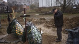 Muž smúti pri hrobe zabitých civilistov v meste Buča.
