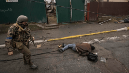 ukrajinský vojak vedľa mŕtveho tela civilistu v meste Buča.