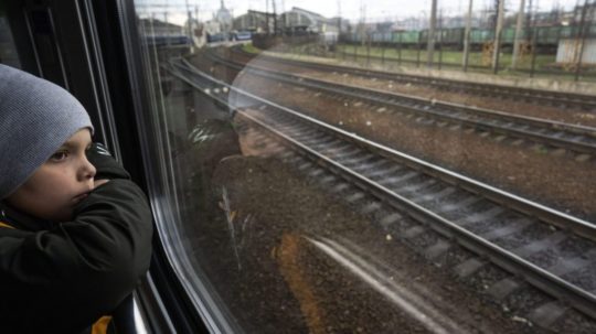 Chlapec sa pozerá z okna vlaku pred príchodom do Ľvova.