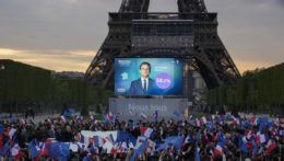 Na snímke voliči úradujúceho prezidenta a kandidáta Emmanuela Macrona sledujú veľkoplošnú obrazovku s predbežnými výsledkami pred Eiffelovou vežou v Paríži.