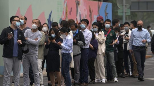 Na snímke obyvatelia a pracovníci úradov s ochrannými rúškami stoja v rade počas hromadného testovania na covid.