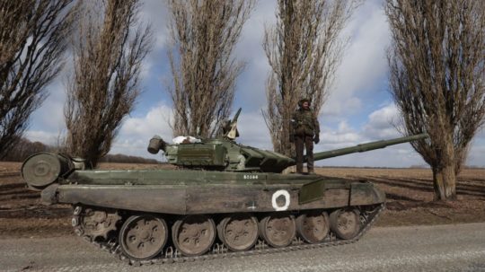 Vojak stojí na tanku v ukrajinskej dedine Lukjanivka.