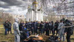 Francúzski forenzní vyšetrovatelia, ktorí prišli na Ukrajinu kvôli vyšetrovaniu vojnových zločinov, stoja bedľa masového hrobu v ukrajinskom meste Buča.