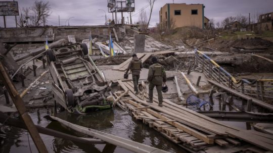 Ukrajinskí vojaci kráčajú cez zničený most v meste Irpiň.