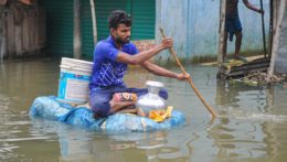Muž na po domácky vyrobenom člne v zaplavených uliciach Bangladéšu.