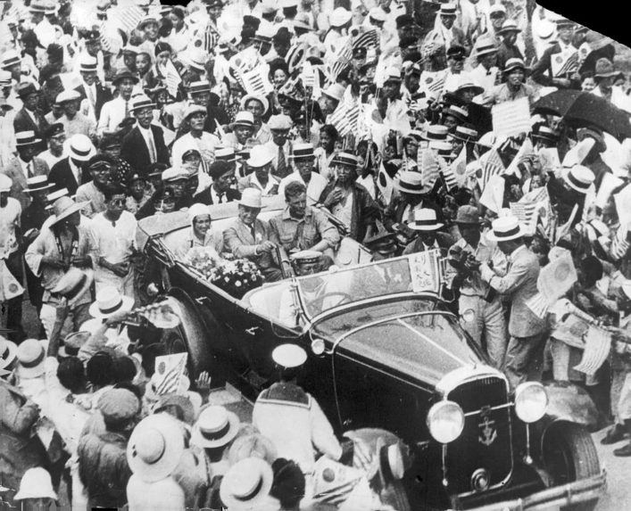 Na snímke Charles Lindbergh a jeho žena v aute, obklopení davmi ľudí, ktorí ich vítajú v Japonsku, neďaleko Tokya.