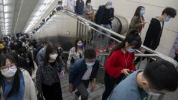Ľudia s ochrannými rúškami kráčajú na stanici metra v čínskom Pekingu.