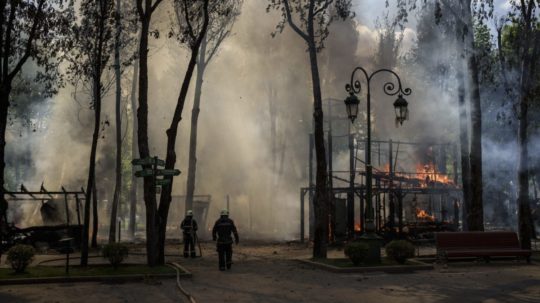 Hasiči bojujú s požiarom v parku po ruskom bombardovaní Charkova.