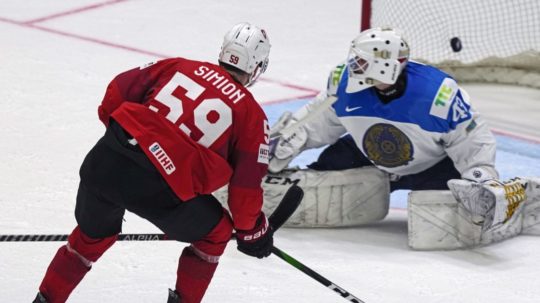 Švajčiarsky hokejista Dario Simion strieľa gól kazašskému brankárovi Andrijovi Šutovovi.
