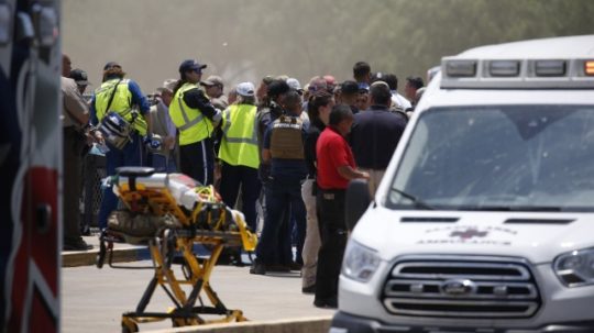 Na fotografii vidno viacero áut a príslušníkov záchranných služieb a prázdne nosítka pred školou v texasa, v ktorej došli k streľbe