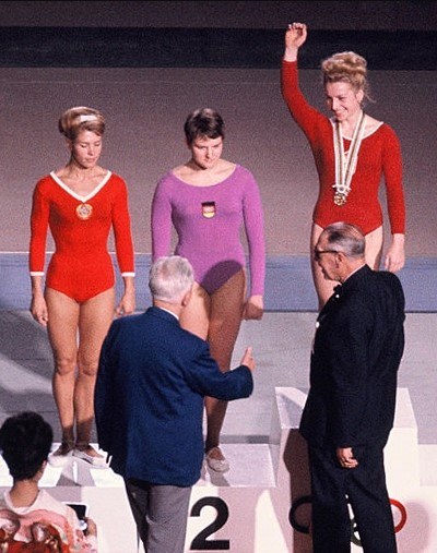 Zlatá medailistka Věra Čáslavská (vpravo) z Československa, strieborné medailistky Larisa Latynina (vľavo) zo Sovietskeho zväzu a Birgit Radochla (uprostred) z Nemecka na pódiu počas odovzdávania medailí počas OH v Tokiu v roku 1964.