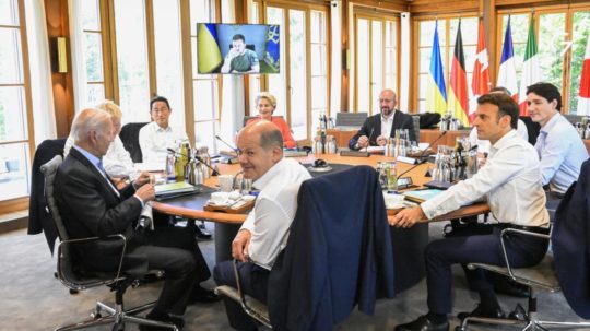 Nemecký kancelár Olaf Scholz (uprostred), americký prezident Joe Biden (vľavo) a francúzsky prezident Emmanuel Macron (vpravo) spolu s ďalšími lídrami skupiny G7 počas rokovania za okrúhlym stolom.