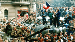 Na archívnej snímke z 21. augusta 1968 mladí ľudia stoja na prevrátenom vozidle a držia československú vlajku, keď ľudia obkľúčili sovietske tanky v centre Prahy po vpáde vojsk Varšavskej zmluvy na územie Československa.