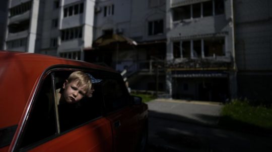 Na archívnej snímke z 31. mája 2022 deti čakajú v aute na príbuzných pred obytnou budovou zničenou po ruskom ostreľovaní v meste Boroďanka v Kyjevskej oblasti.