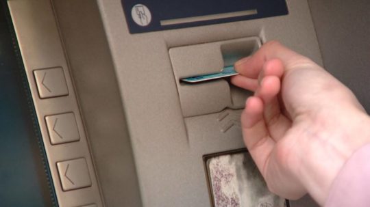 Človek vkladá kartu do bankomatu