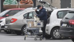 Na snímke muž dáva do kufra auta nákup z nákupného košíka.