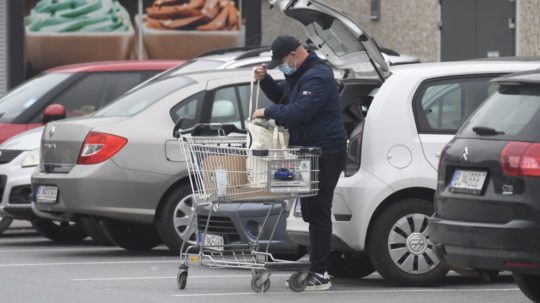 Na snímke muž dáva do kufra auta nákup z nákupného košíka.