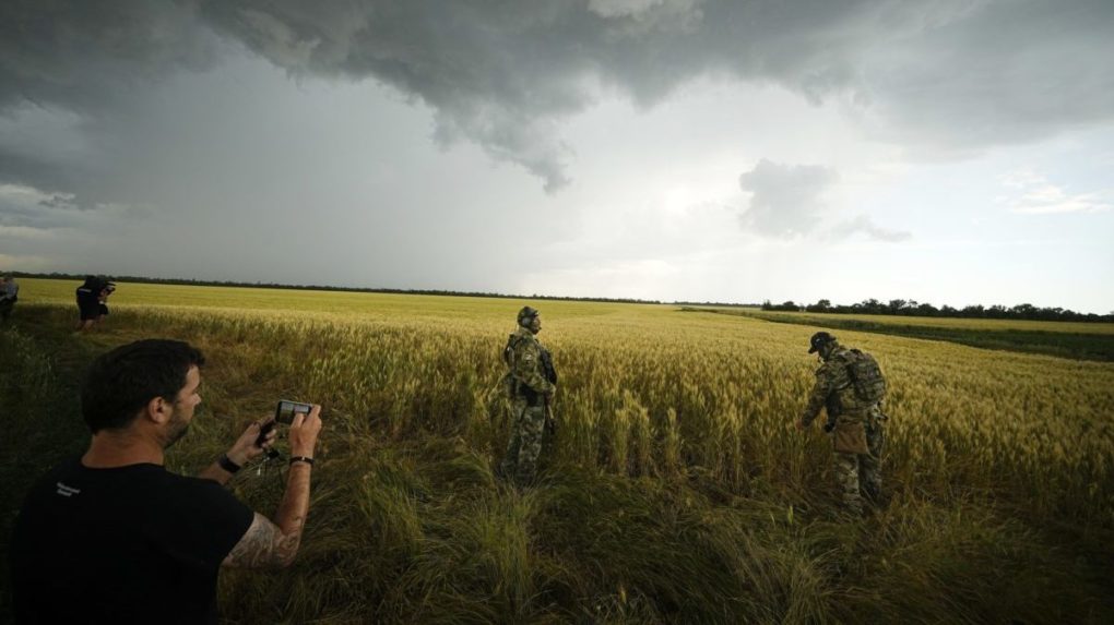 Zahraničný novinár fotí ruských vojakov, ktorí strážia územie vedľa poľa so pšenicou v Záporožskej oblasti na juhu Ukrajiny
