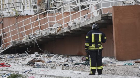 Na snímke hasič stojí vedľa obytného domu poškodeného ruským ostreľovaním.