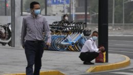 Muži s ochrannými rúškami prechádzajú cez križovatku v čínskom Šanghaji.