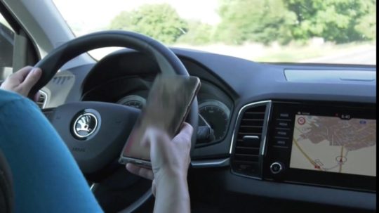 Na snímke žena používa mobil počas šoférovania.