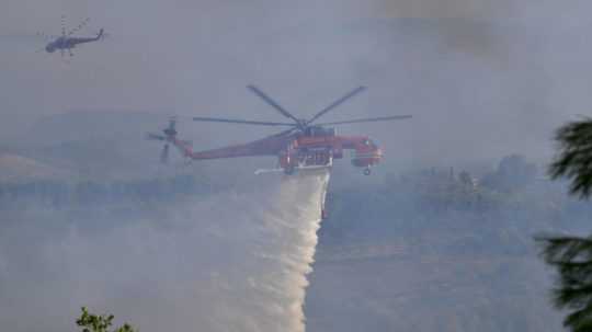 Na snímke vrtuľník hasí požiar neďaleko gréckeho mestečko Olympia.
