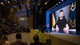 Na veľkoplošnej obrazovke sa počas virtuálneho prejavu prihovára účastníkom konferencie v švajčiarskom Lugane ukrajinský prezident Volodymyr Zelenskyj