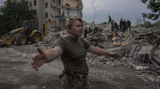 Ukrajinská vojačka usmerňuje novinárov neďaleko zničenej obytnej budovy v meste Časiv Jar.