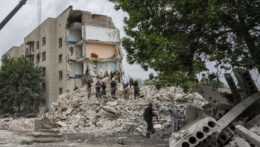 Záchranári stoja v troskách zničenej obytnej budovy po ruskom raketovom útoku v meste Časiv Jar na východe Ukrajiny.