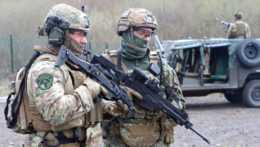 Na snímke sú profesionálni vojaci držiaci pušky pred terénnym vozidlom.