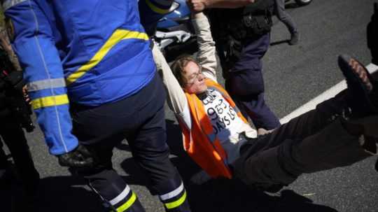 Francúzska polícia odnáša jedného z aktivistov preč z trate.