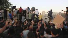Demonštranti preliezajú plot irackého parlamentu.